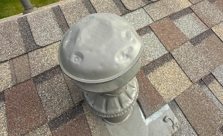 Hail-dented roof vent and bruised shingles on a Pflugerville home
