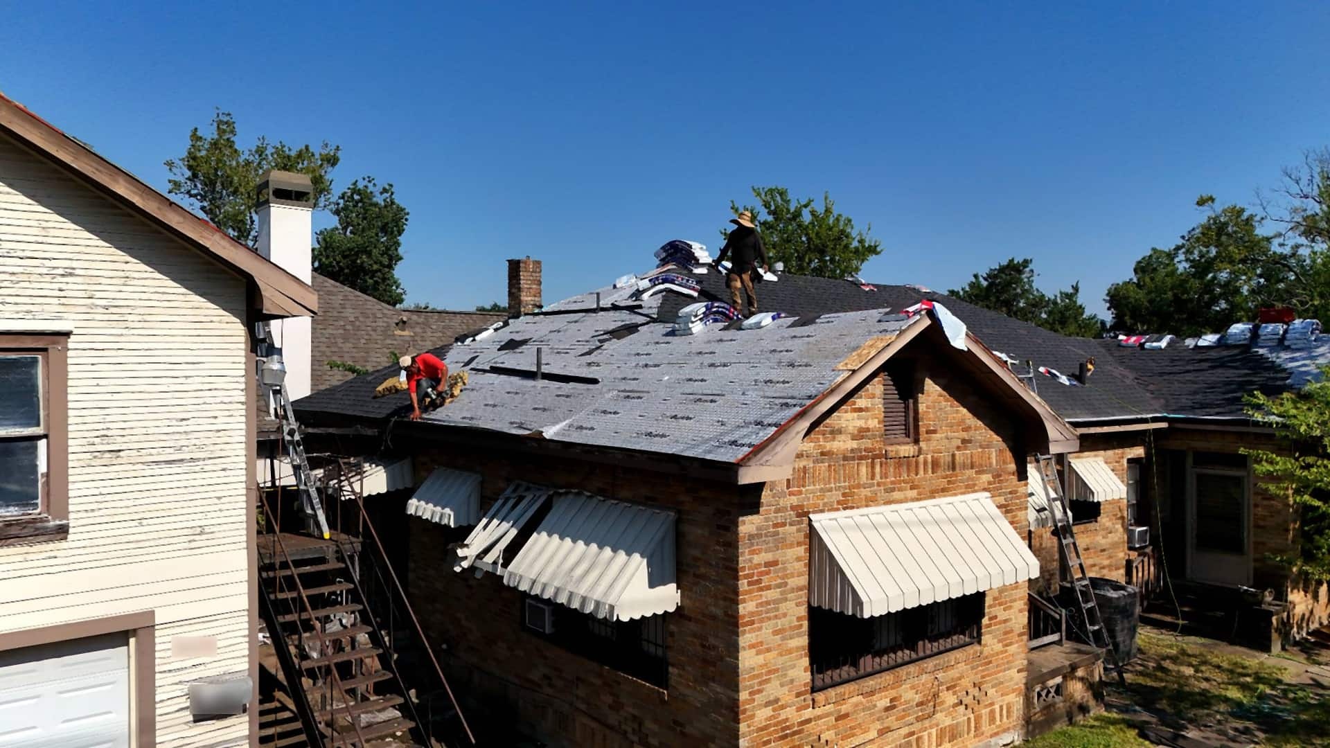 Tex Roof crew tearing off old shingles and installing new decking during a roof replacement in Austin