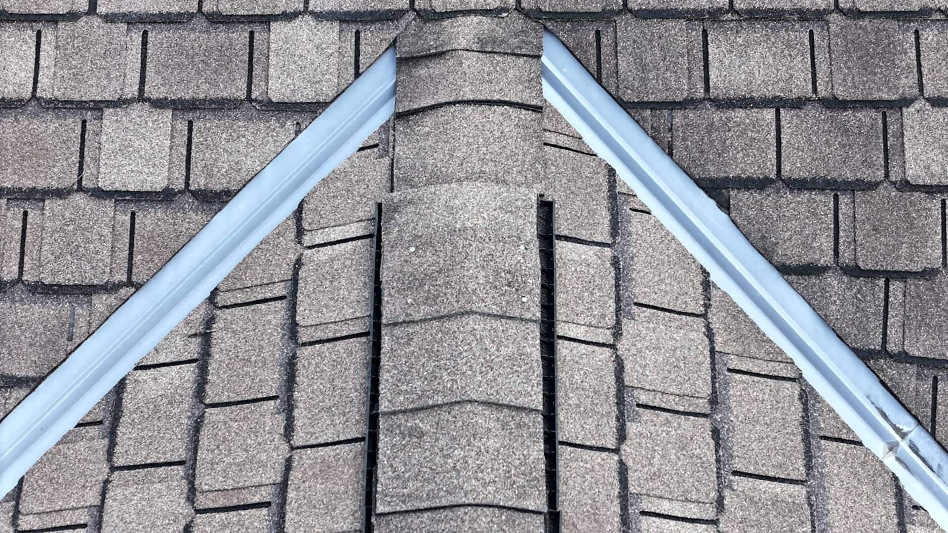 Roof inspector checking chimney flashing and shingle condition on an Austin home