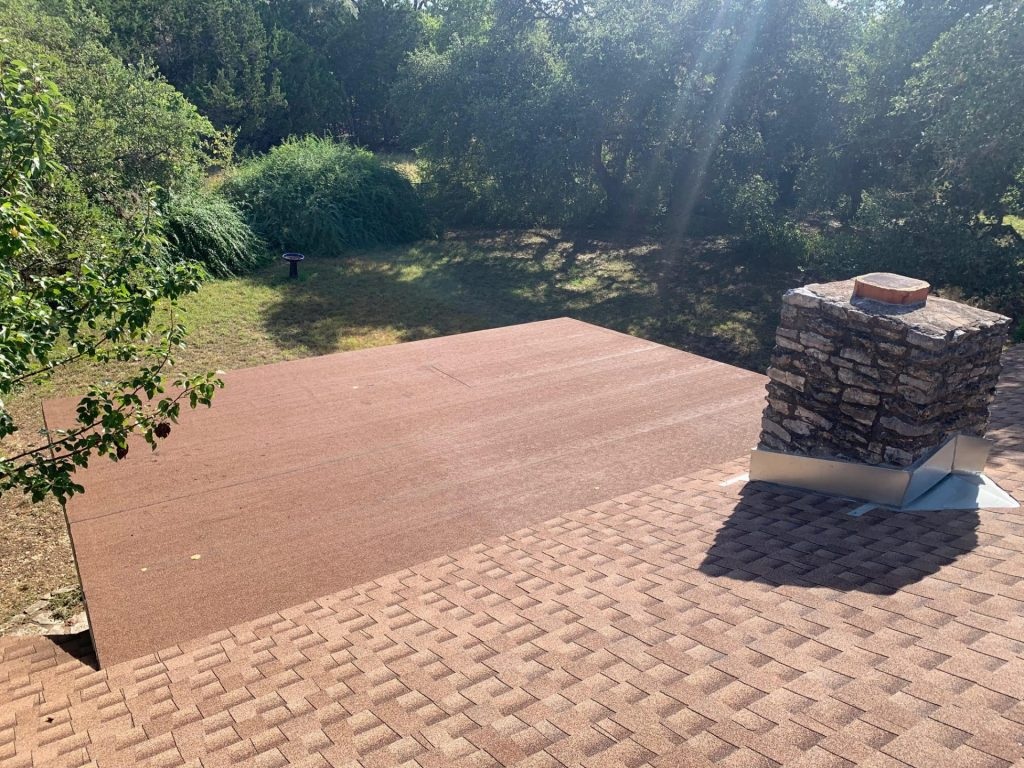 Roofer applying reflective coating to a commercial flat roof in Austin