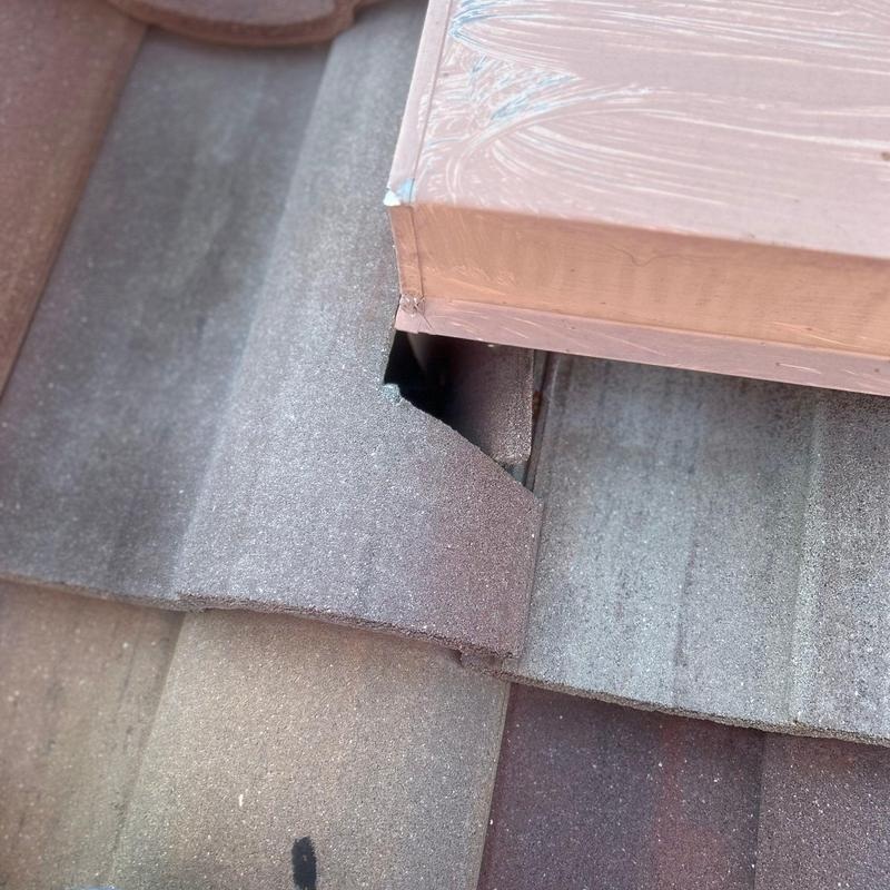 Roofer lifting clay tiles to replace failed underlayment on an Austin home