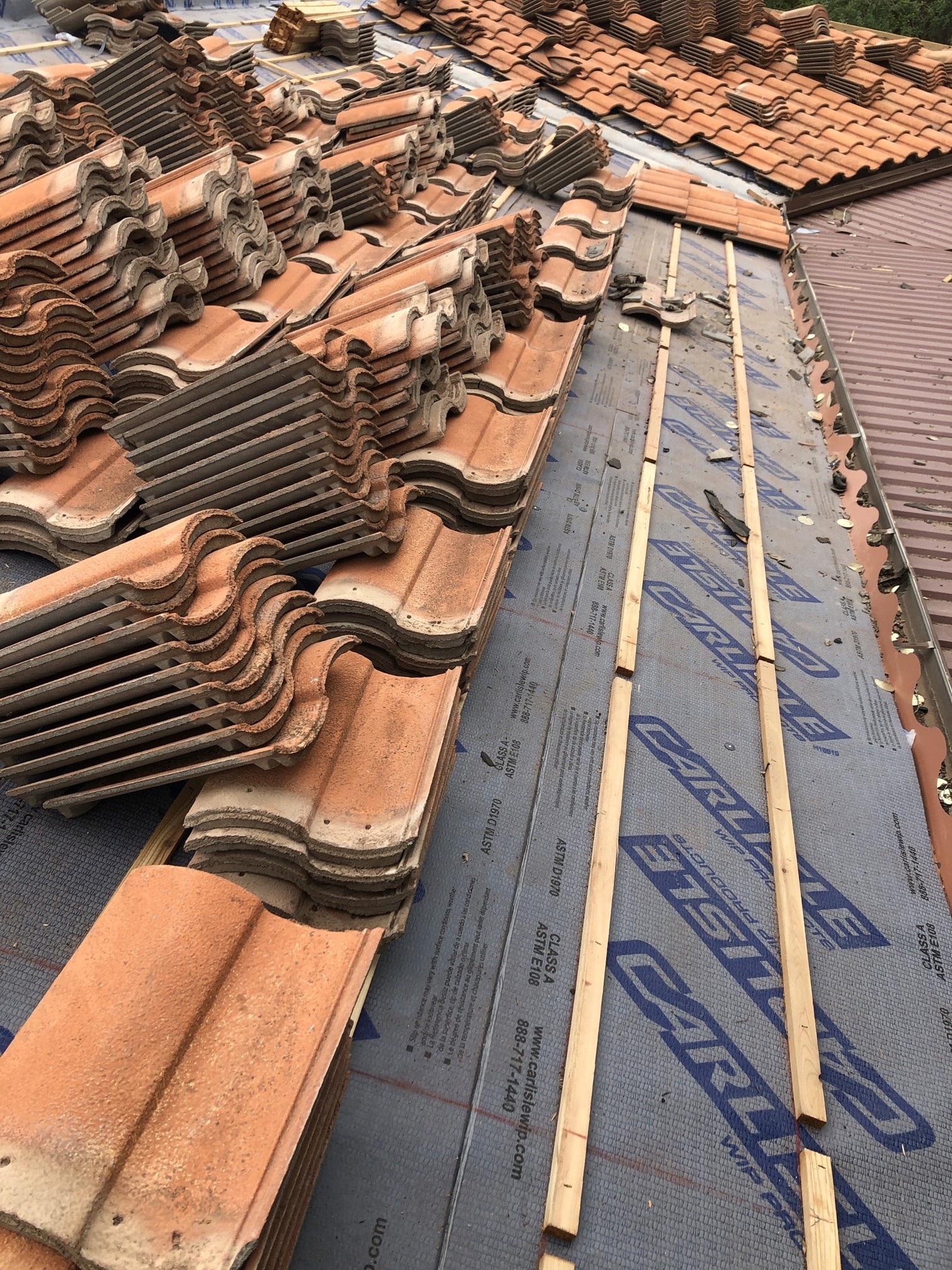 New high-temperature underlayment being installed beneath clay tiles during a lift and relay