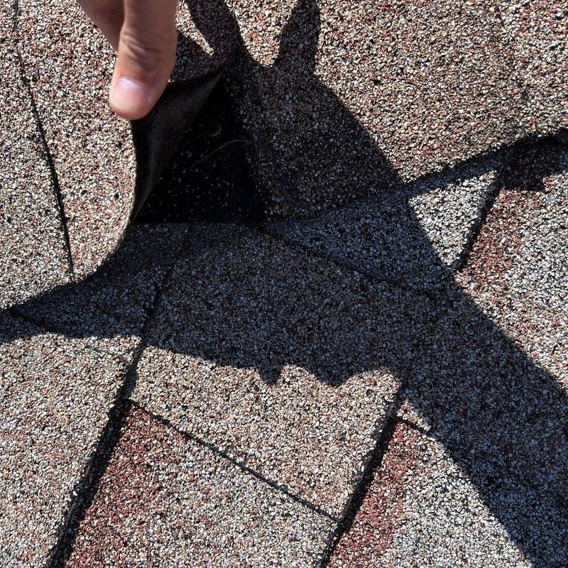 Wind-creased and lifted shingles on a Kyle home after a spring storm